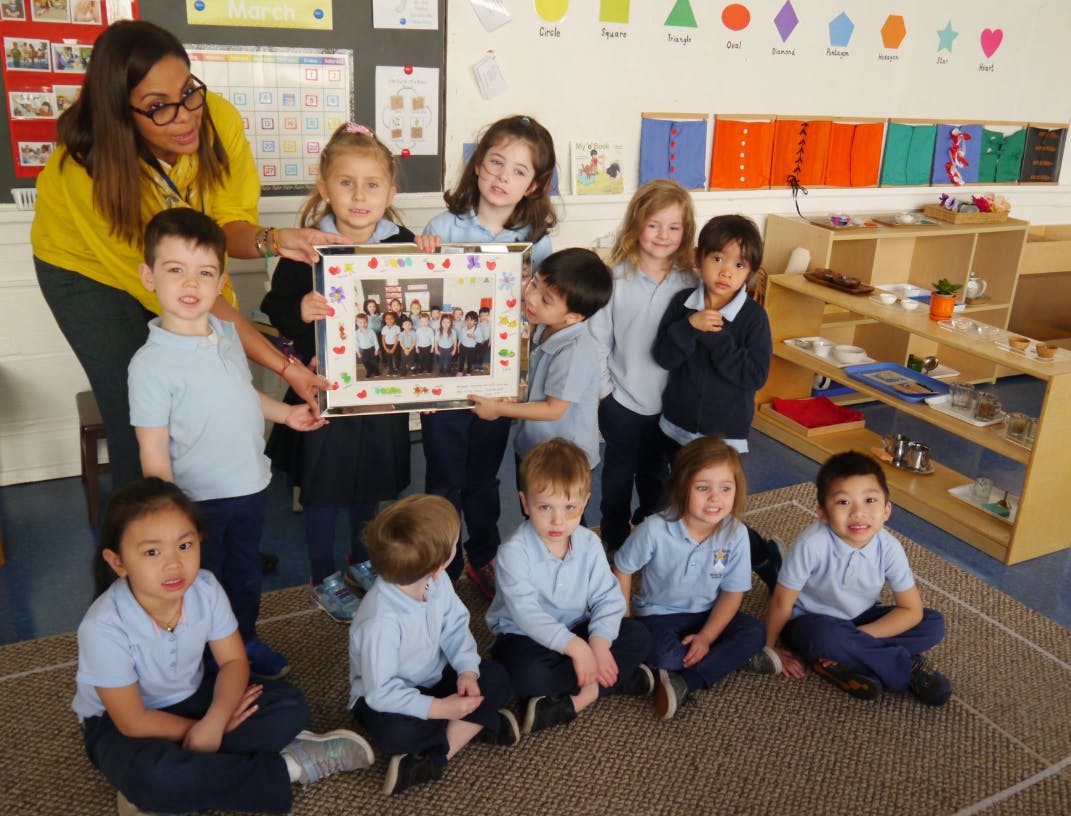 Adult and children holding a framed photo in a classroom