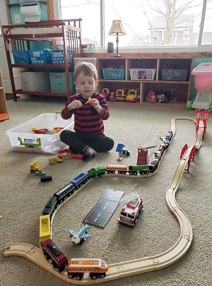 Child playing with a toy train set on the floor