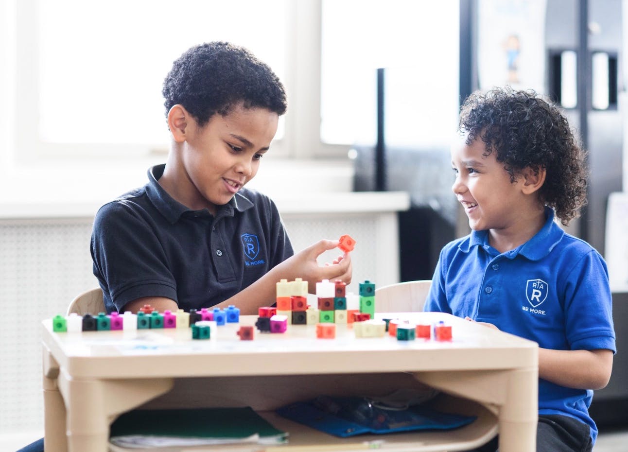 Two children playing with colorful building blocks at a table