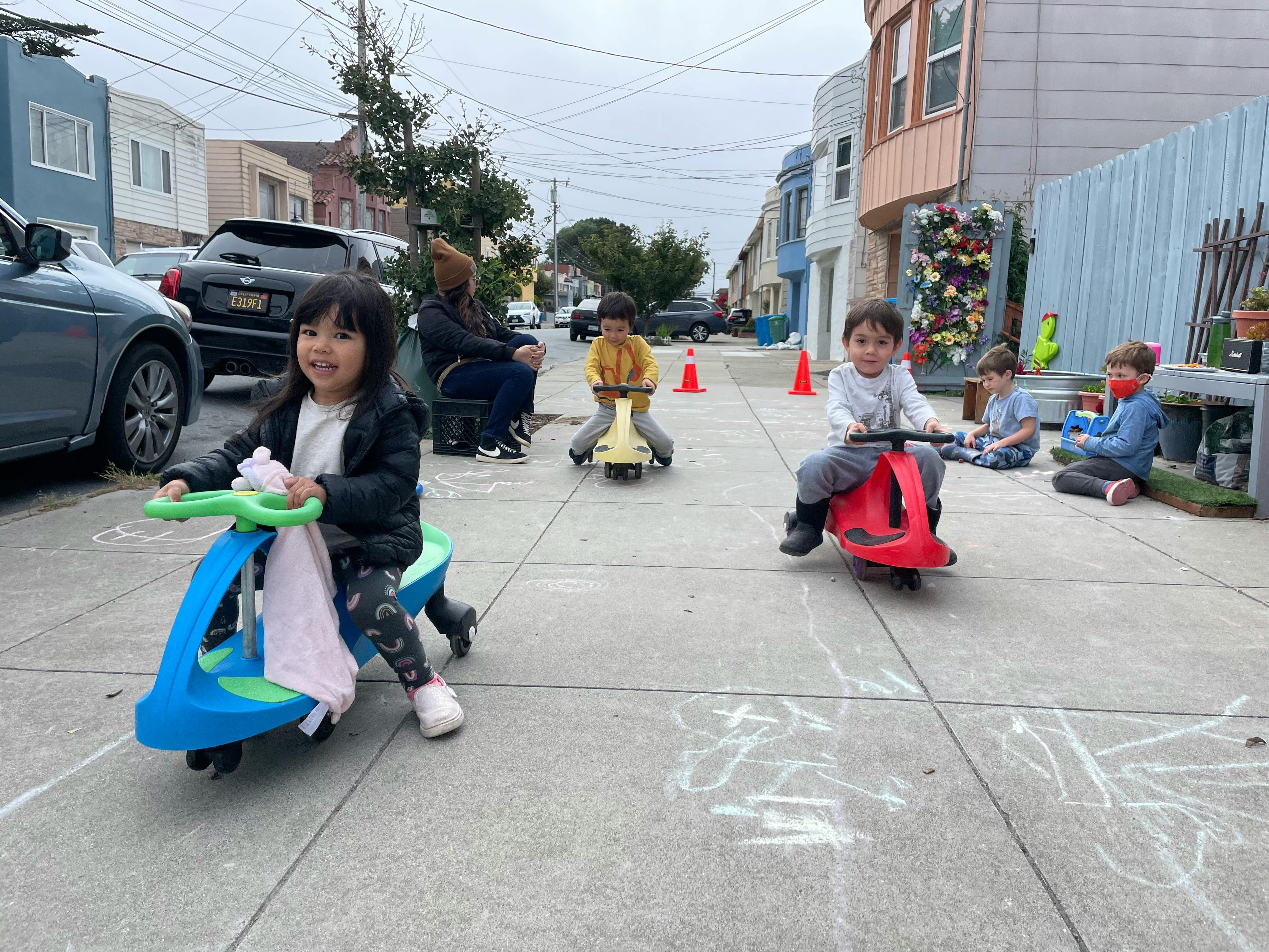 Children riding toy scooters on a sidewalk