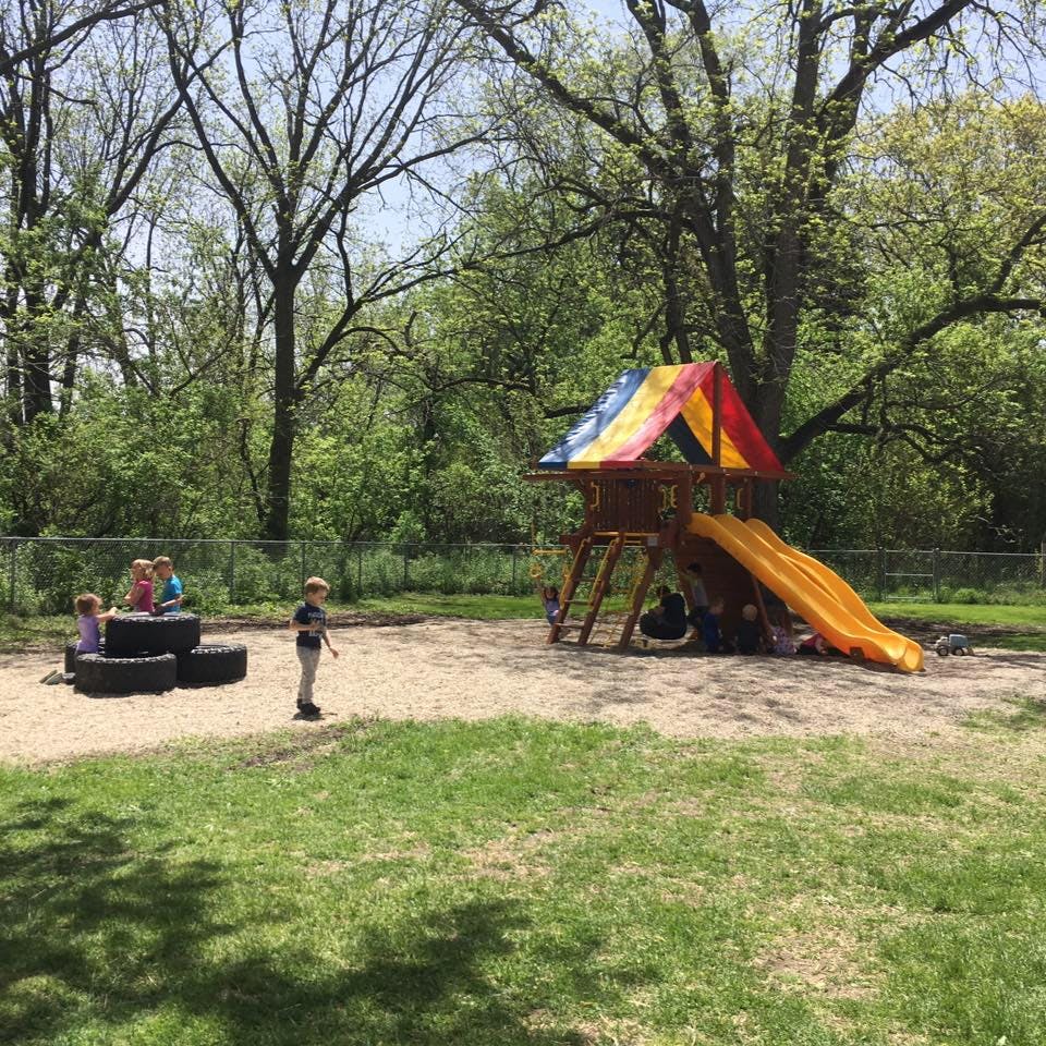 Children playing on a playground with a slide and tires
