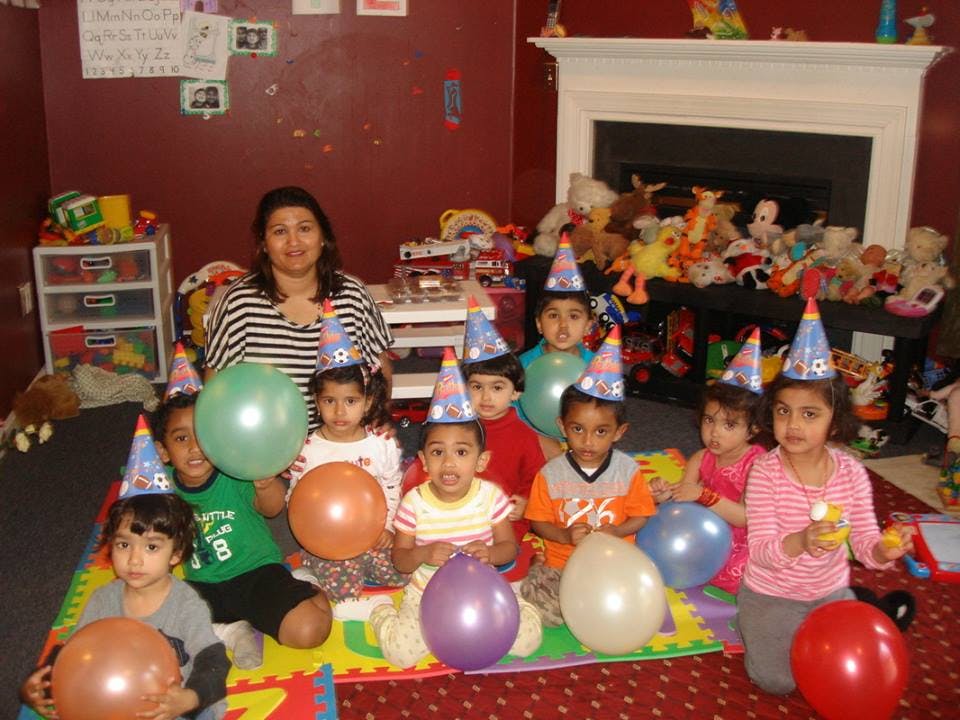 Adult and children wearing party hats, holding balloons