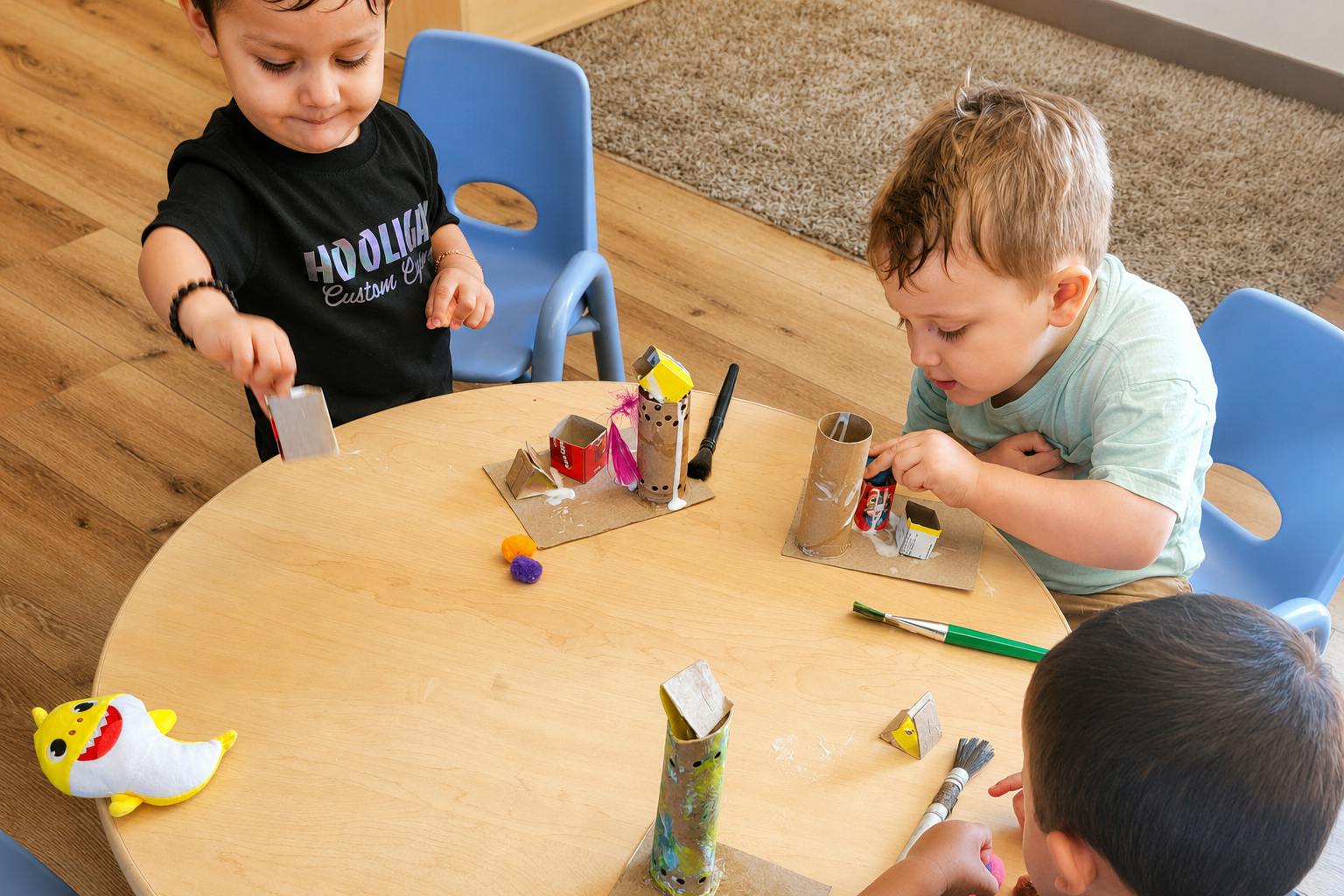 Three children working on cardboard crafts at a round table