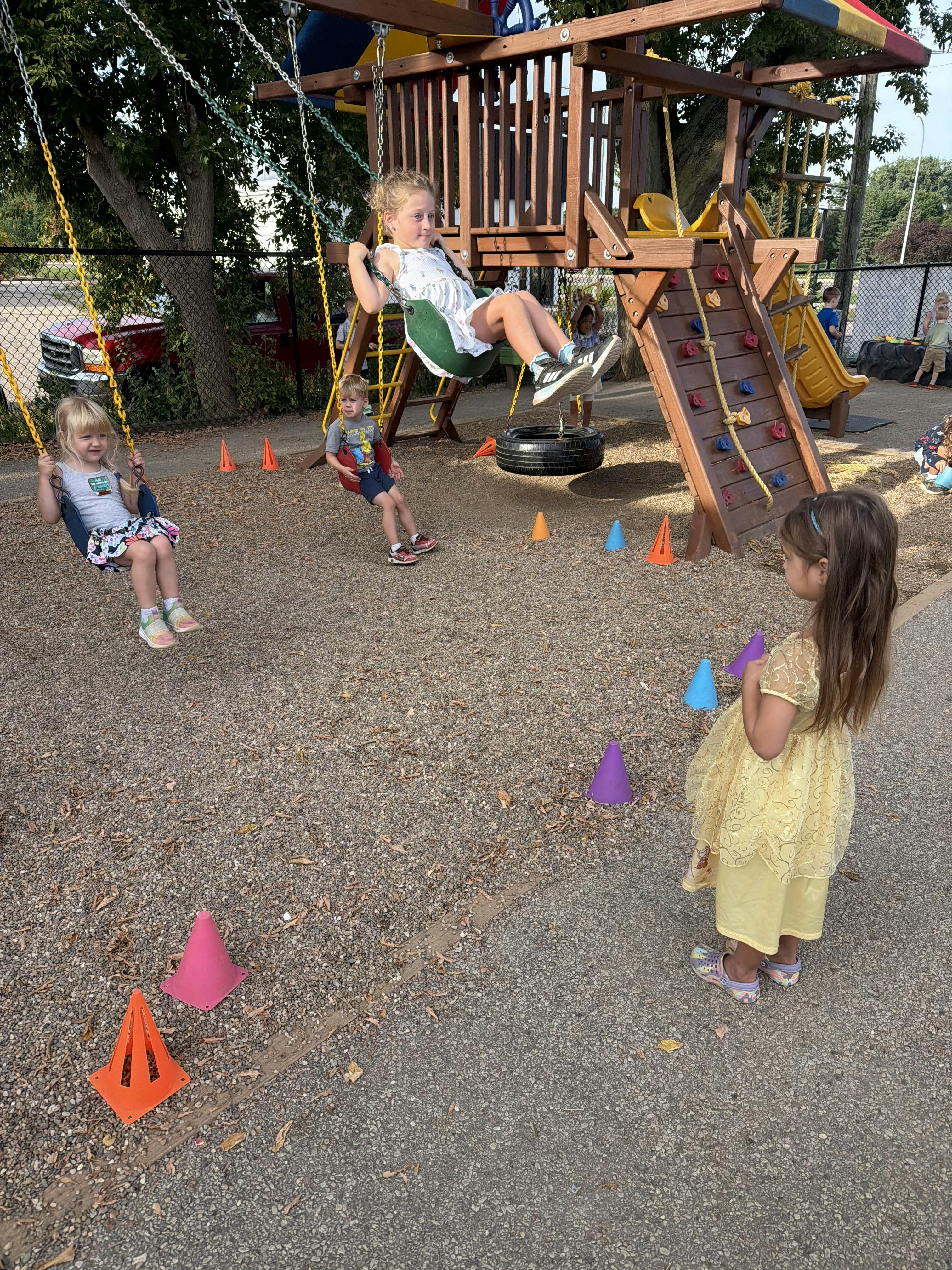 Children playing on swings and a climbing frame at a playground