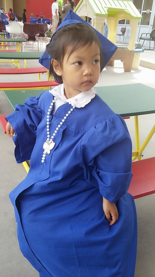 Child in blue graduation gown and cap with a cap