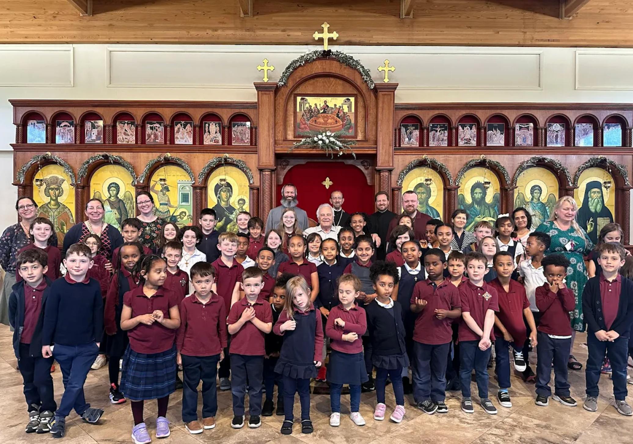 Group of adults and children standing in front of an ornate wooden altar