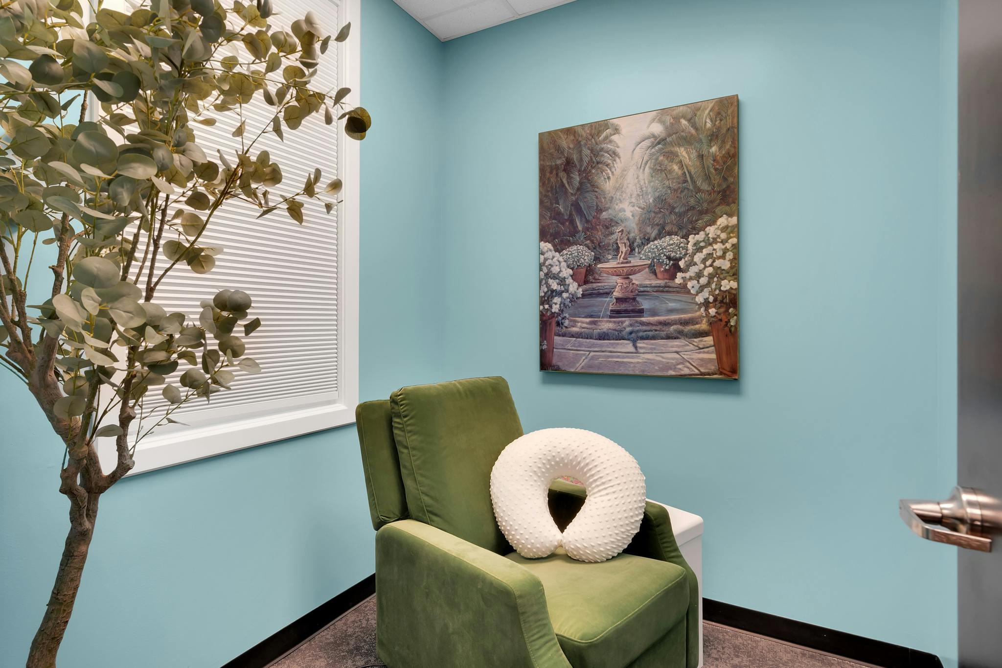 Green recliner with a neck pillow in a room with light blue walls
