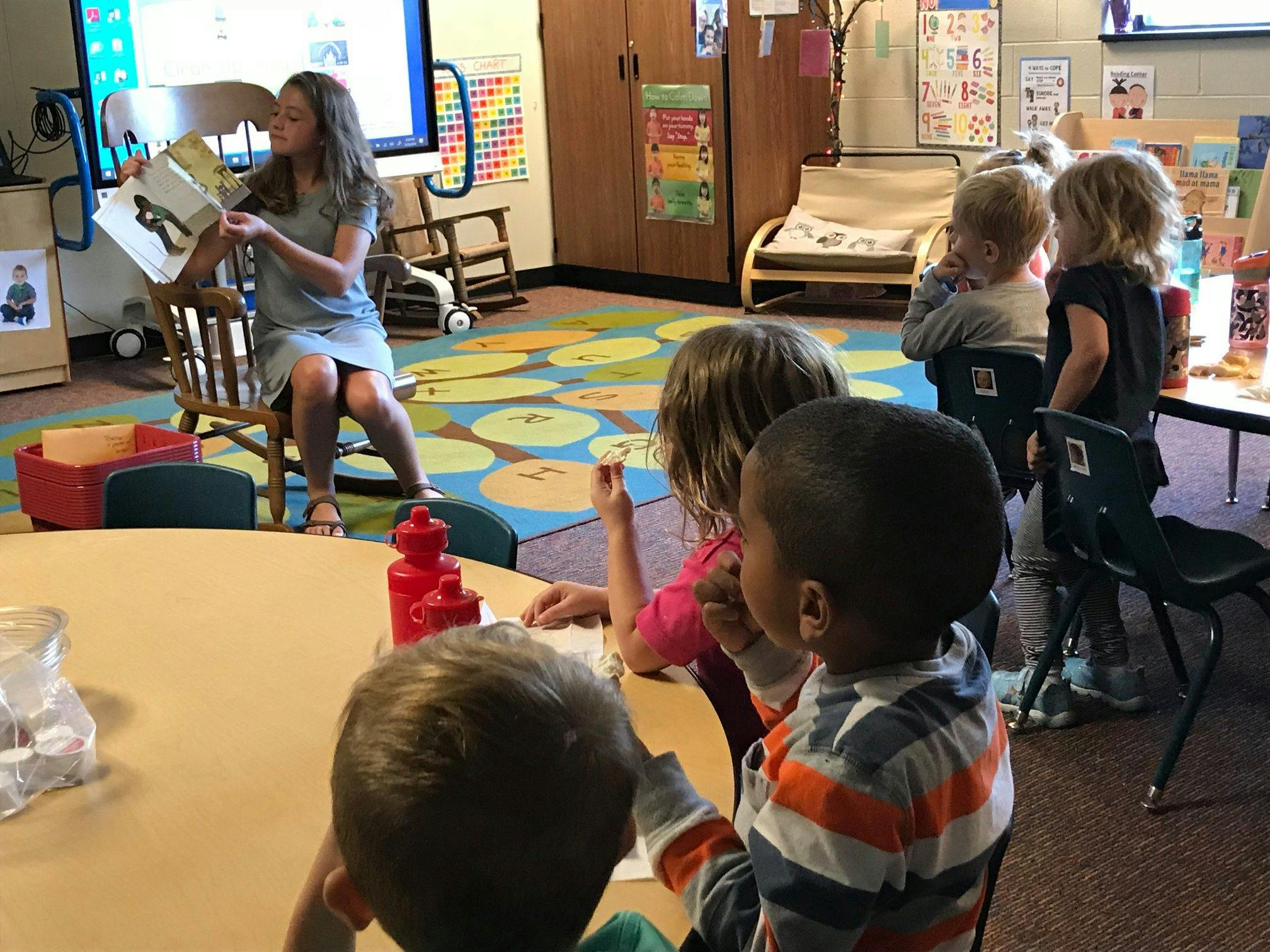 Person reading a book to children in a classroom