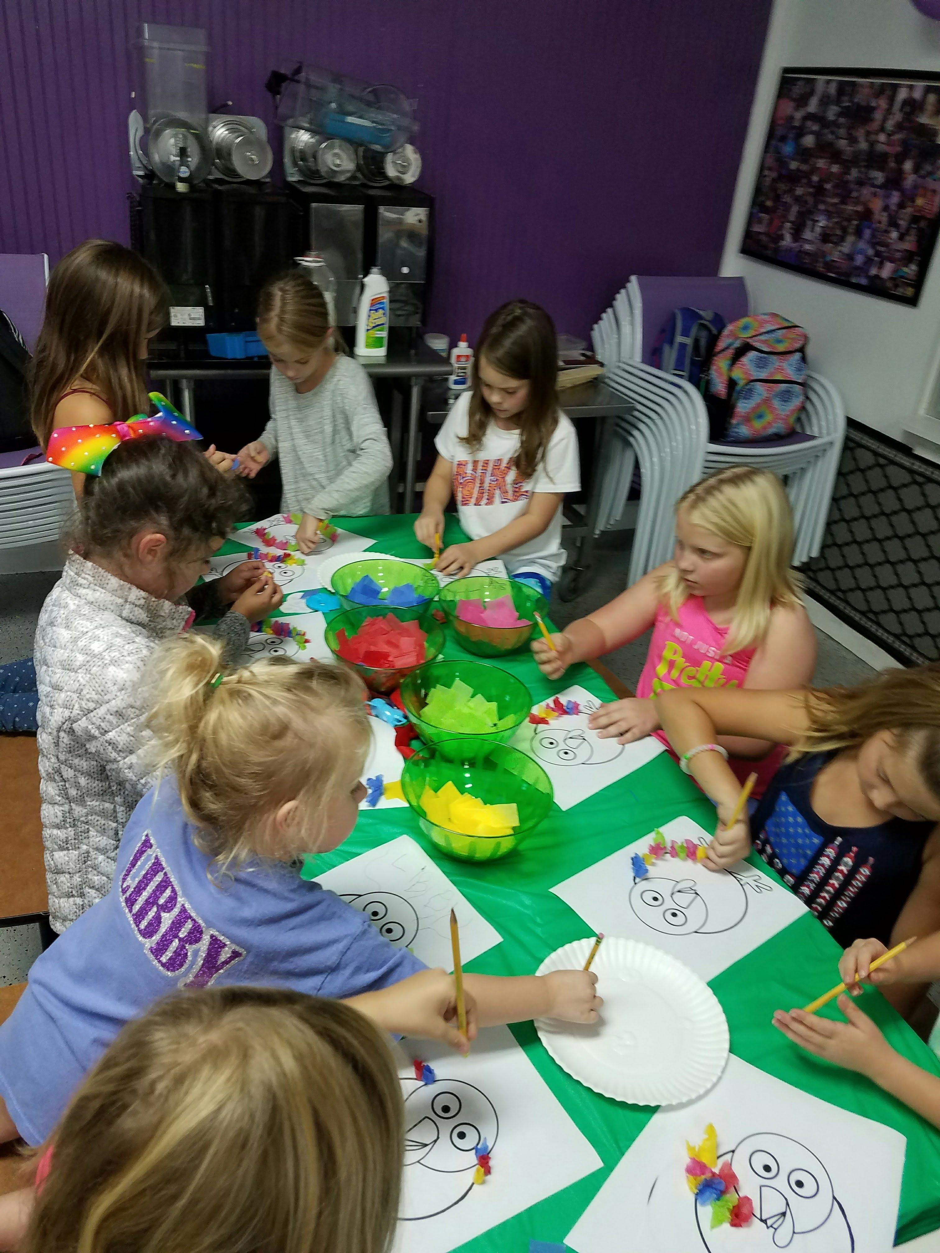 Children sitting at a table coloring drawings