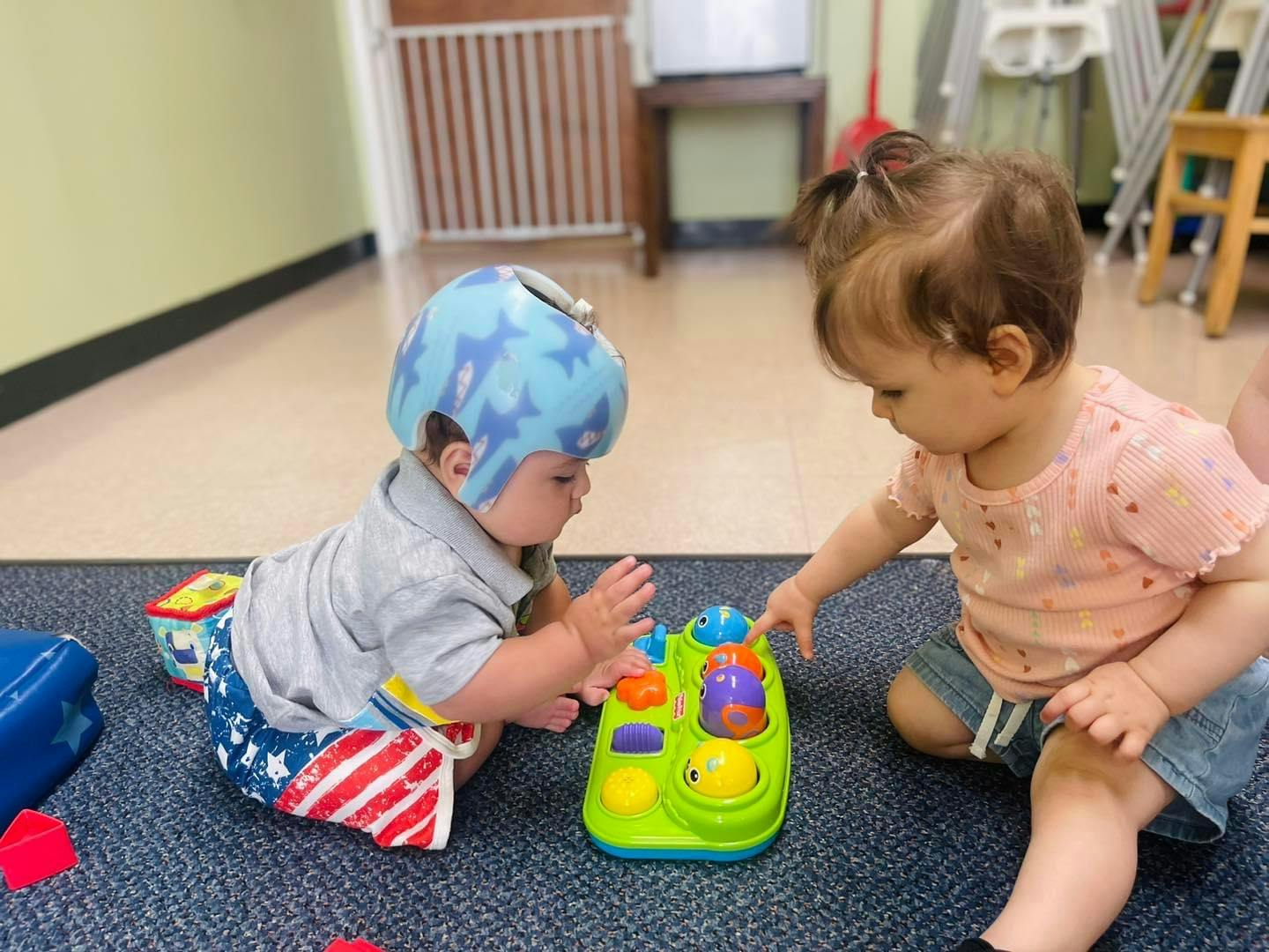 Two children playing with a toy on a rug