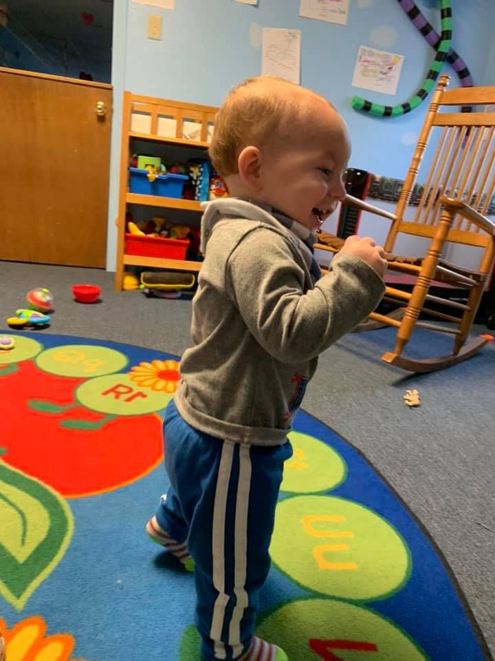 Child standing on a colorful rug in a classroom