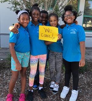 Five children holding a sign that says "We Care!"