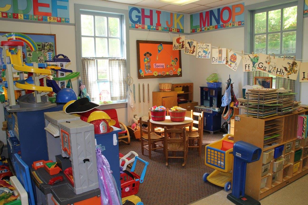 A classroom with toys, small tables and chairs, and alphabet decorations