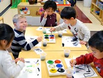 Children painting at a table in a classroom