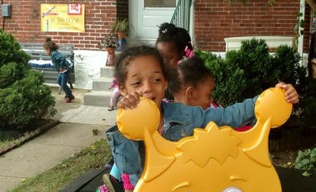Child playing with a yellow toy, other children in background