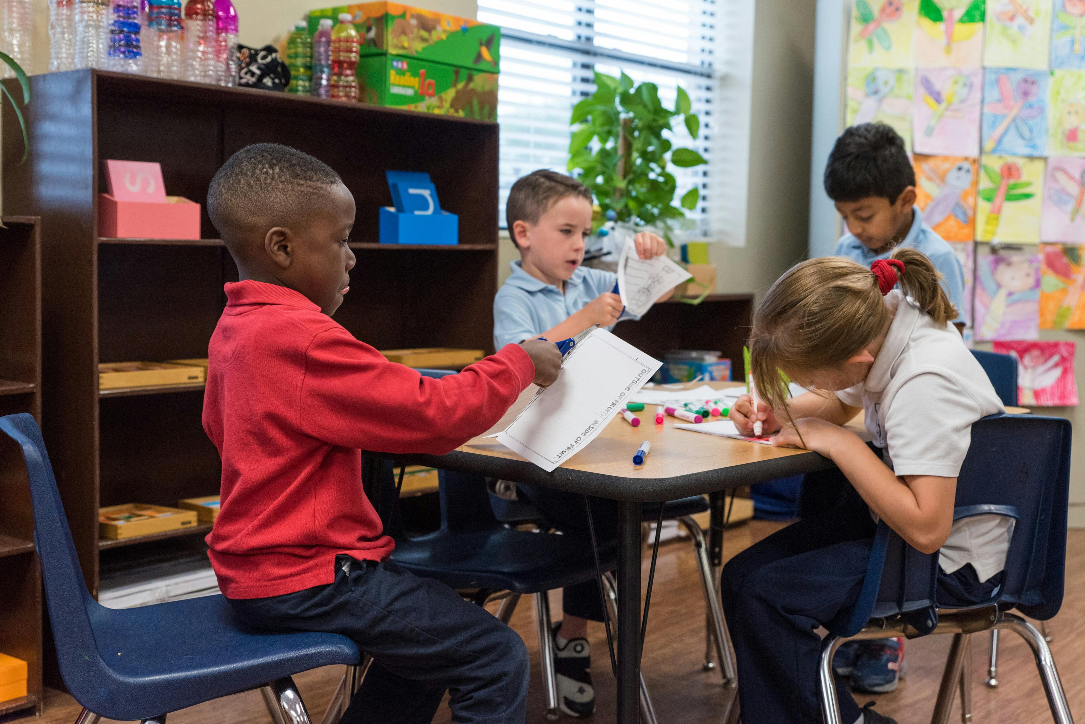 Four children working at a table in a classroom