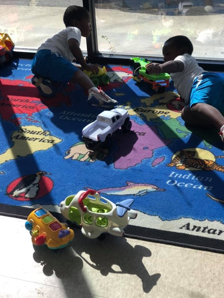Two children playing with toys on a map rug