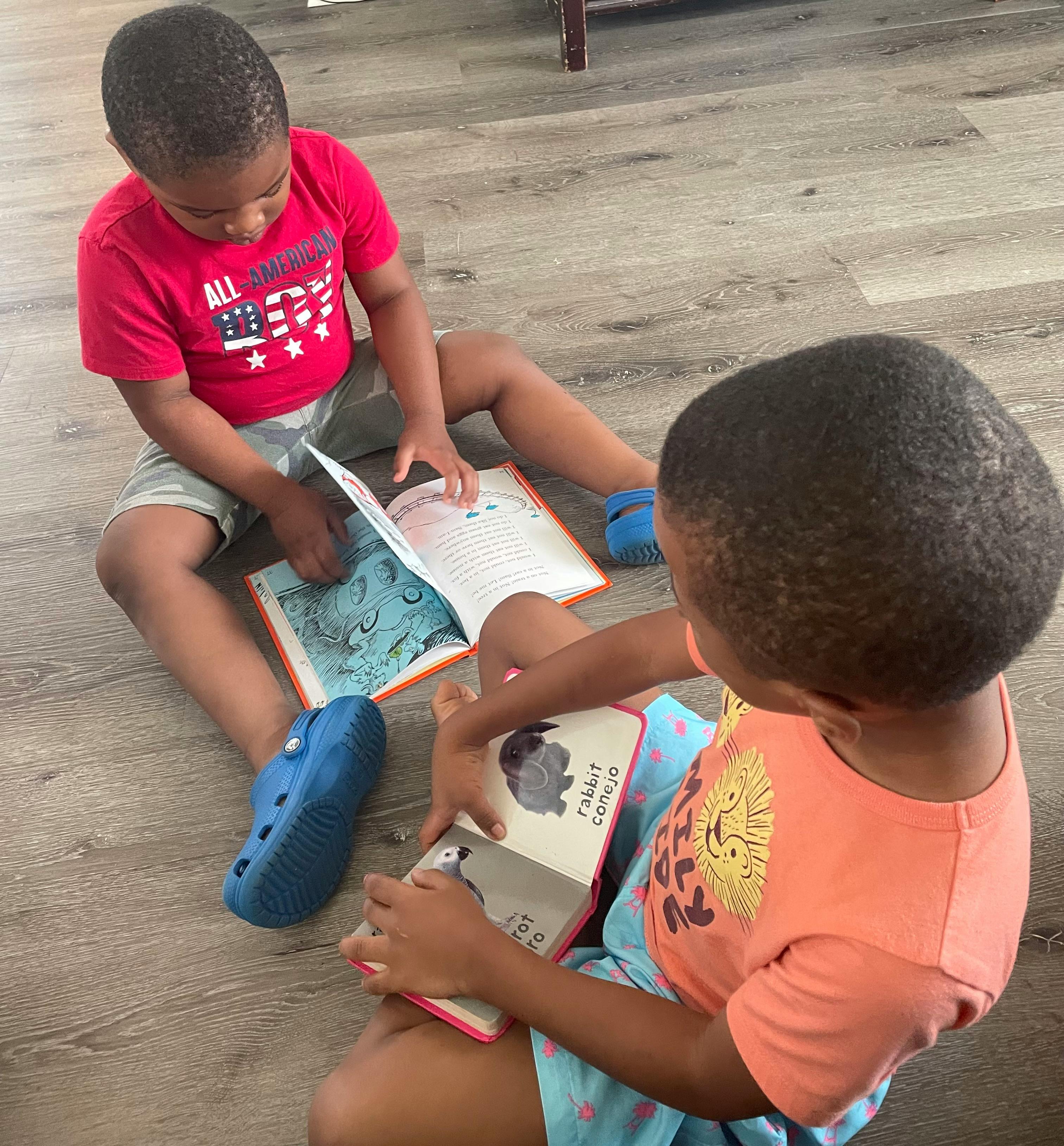 Two children sitting on a floor reading books