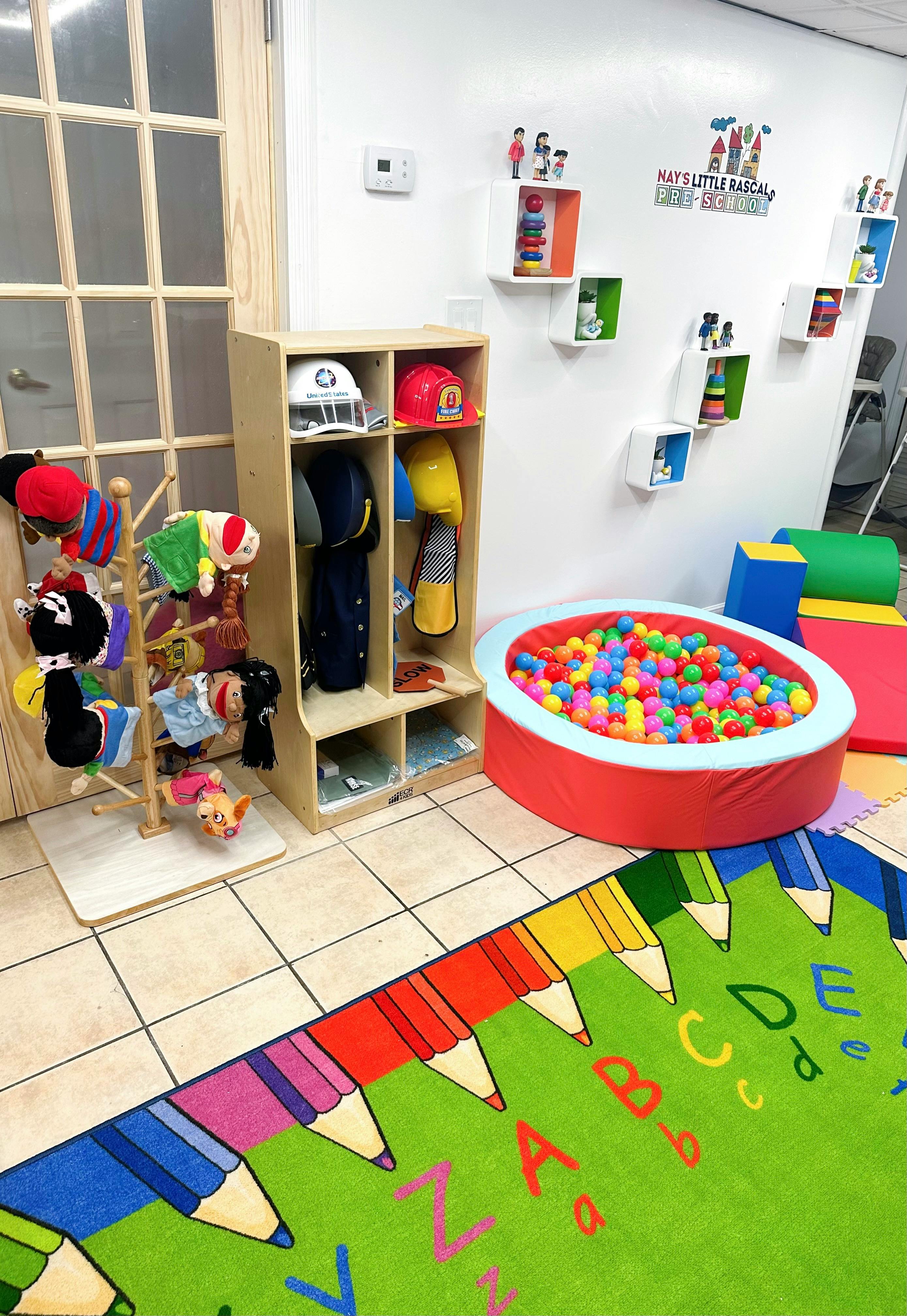 Children's play area with a ball pit, cubbies, and a colorful alphabet rug