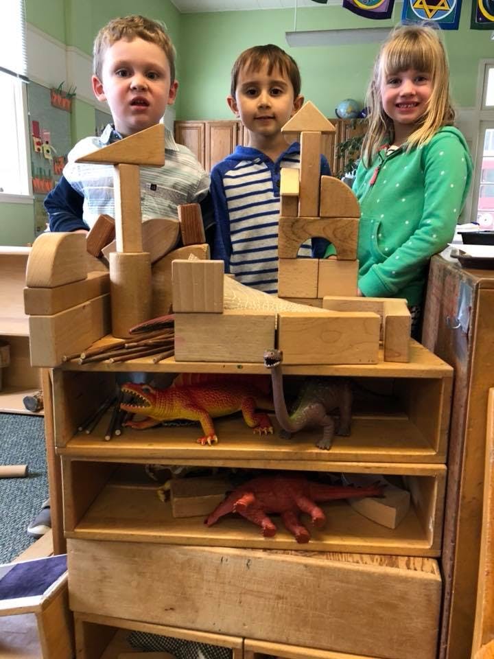 Three children standing behind a wooden block structure