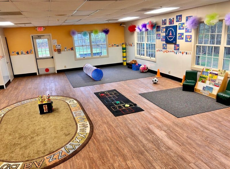 Playroom with alphabet rug, toy tunnel, hopscotch mat, and bookshelves