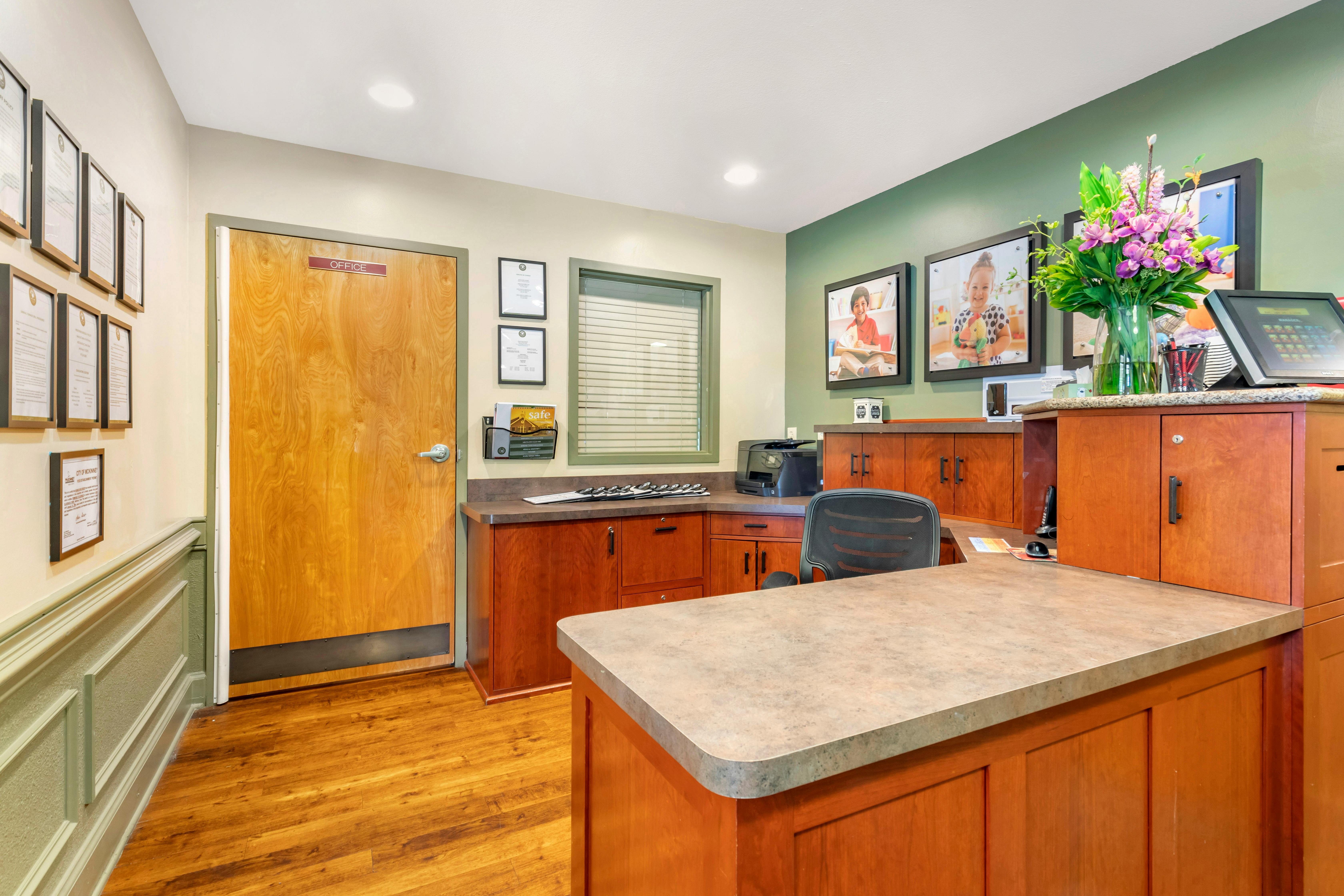 Reception area with a desk, office door, and framed documents on the wall