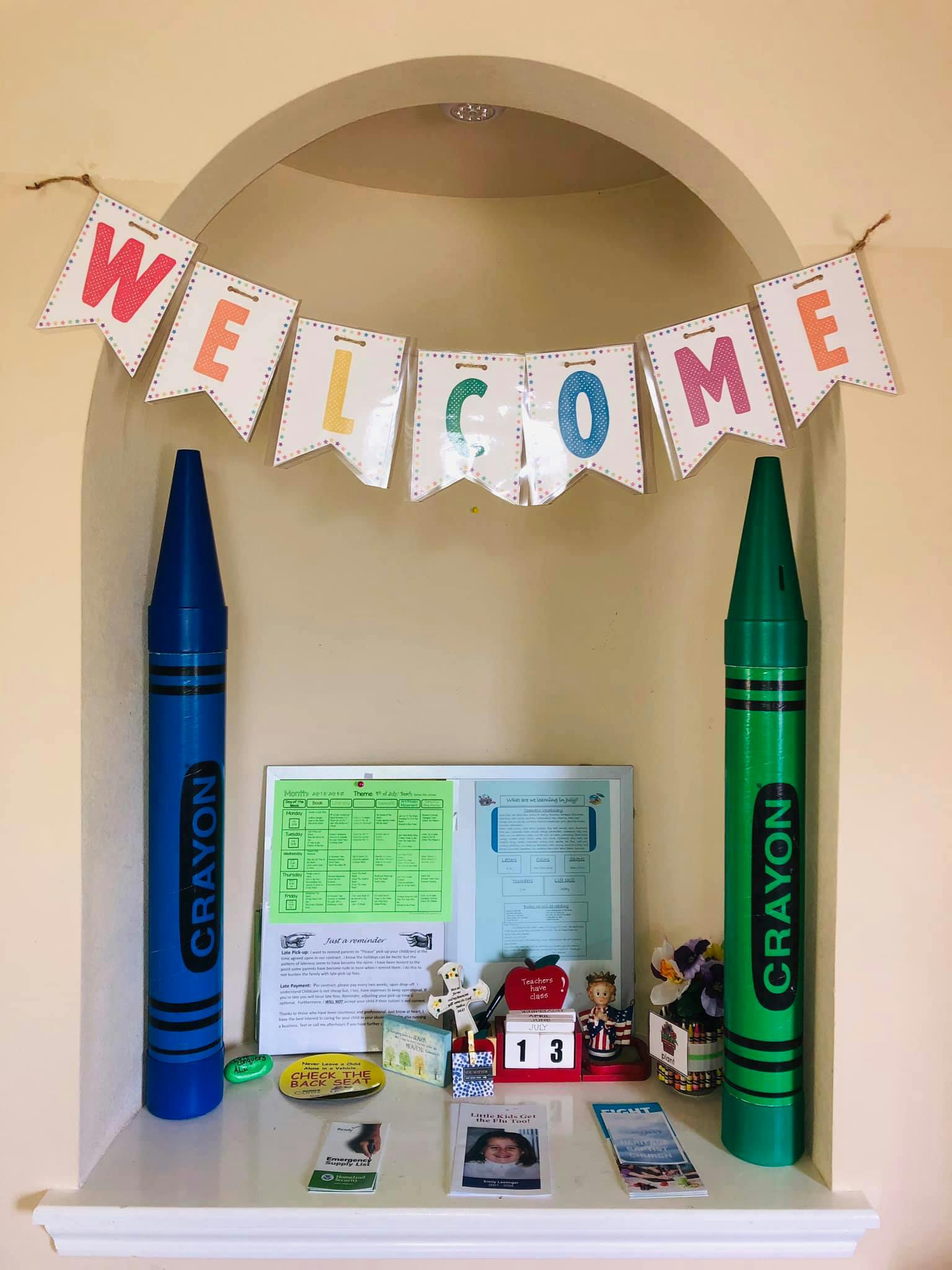 Welcome banner with two large crayon decorations and school supplies