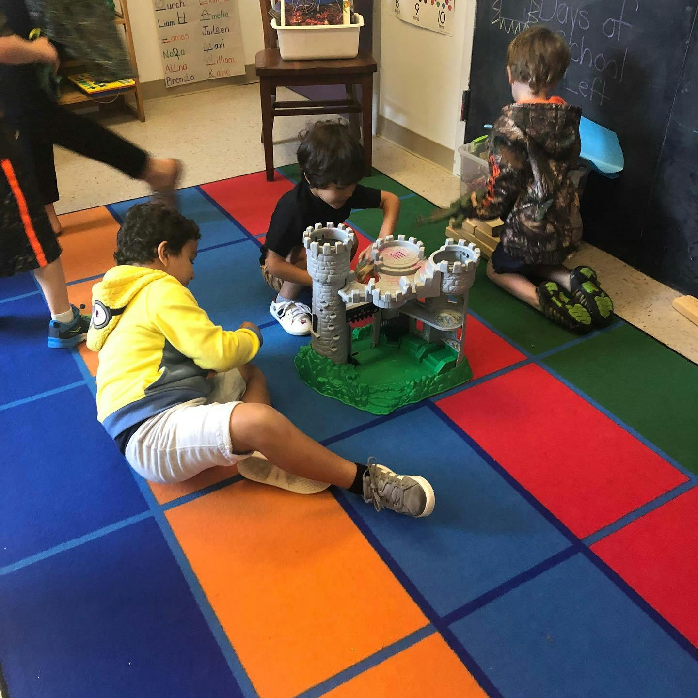 Children playing with a toy castle on a colorful floor