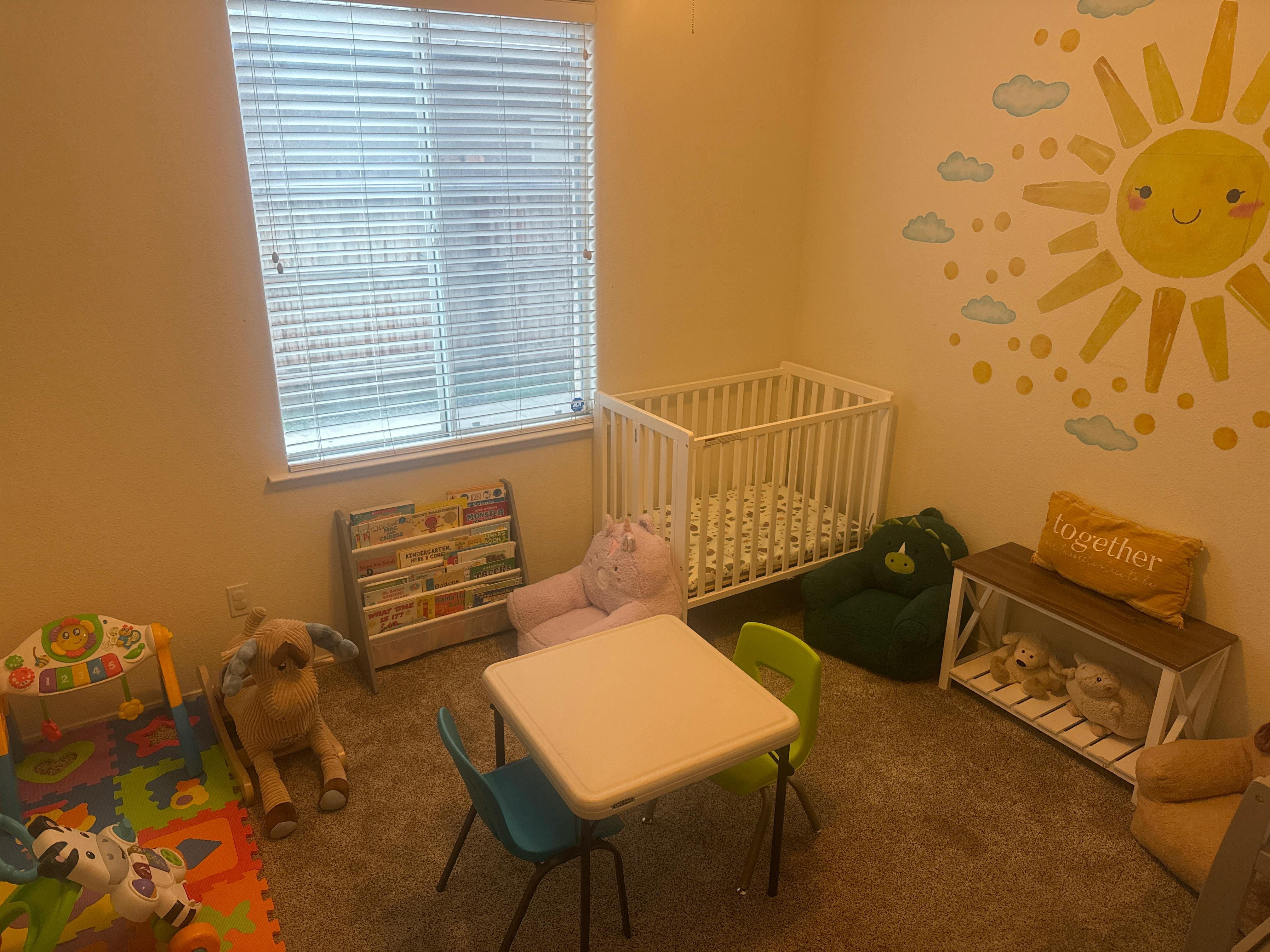 Child's room with a crib, play table, bookshelf, and toys