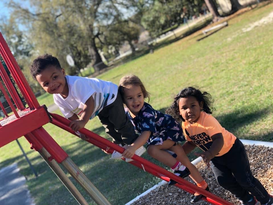 Three children on a red playground slide