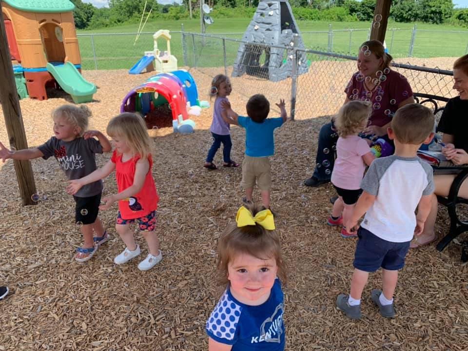 Children and adults on a playground with wood chips