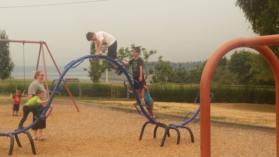 People and children on playground climbing equipment