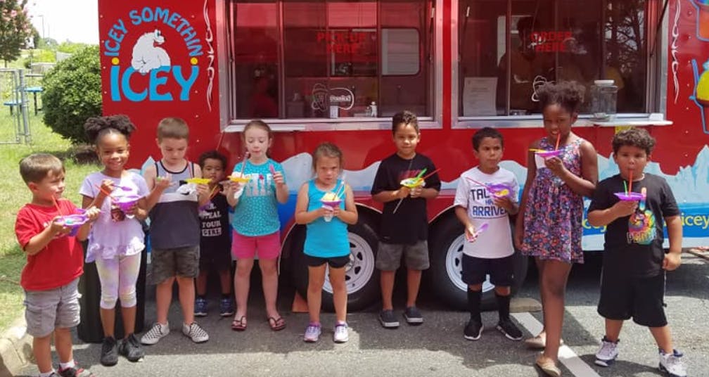 Children holding cups of ice cream in front of a red food truck