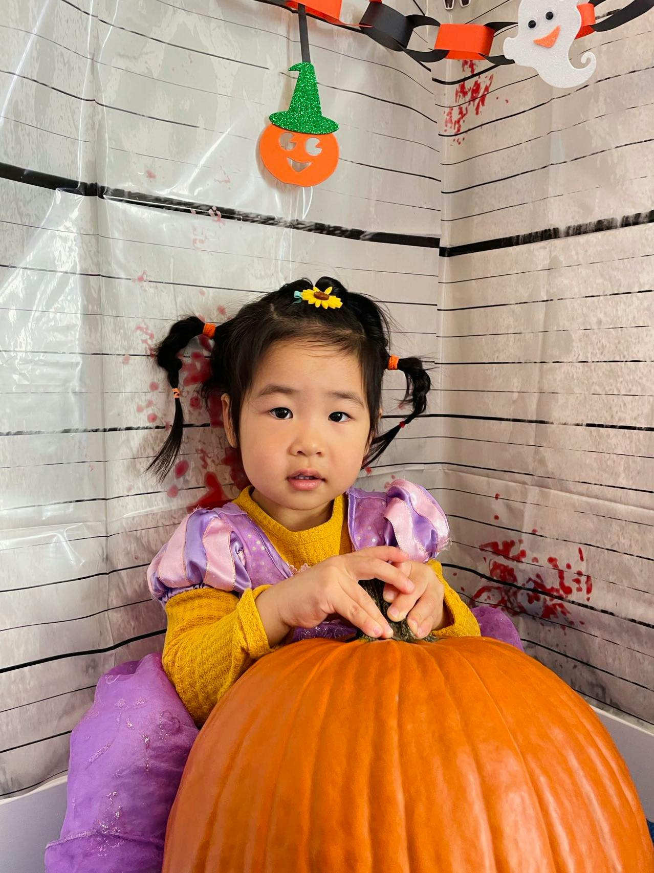 Child in costume with hands on a pumpkin