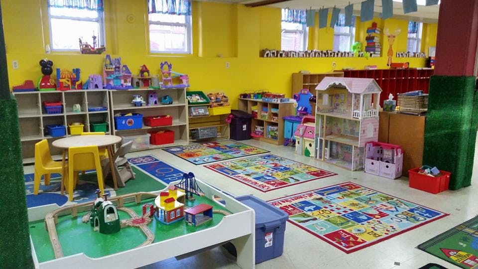 Playroom with colorful rugs, shelves of toys, and a play table