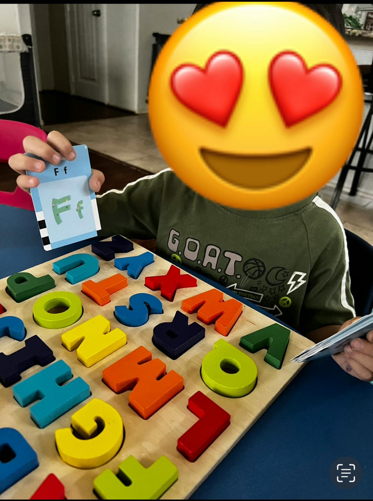 Child holding a flashcard with the letter F, next to an alphabet puzzle