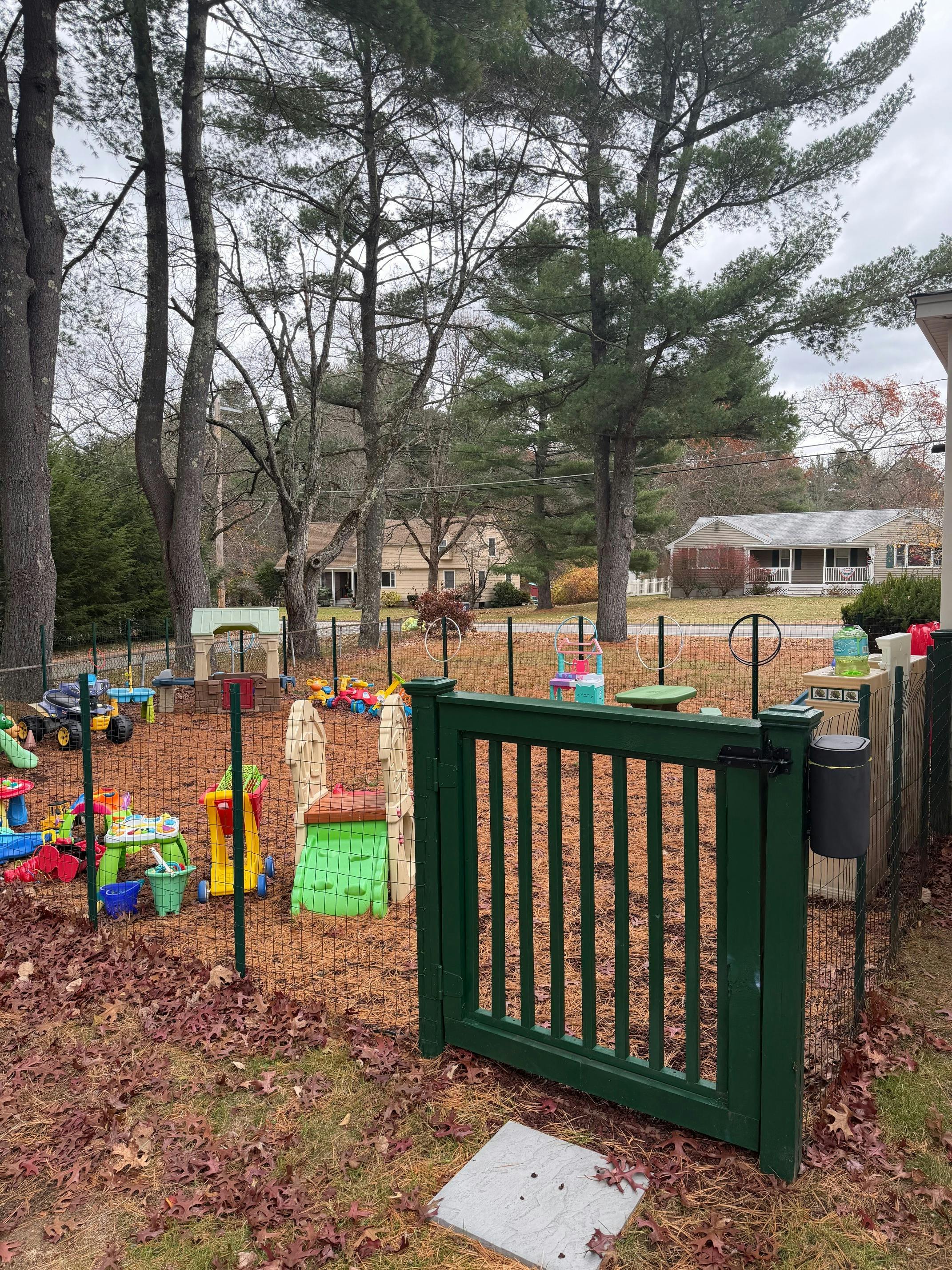 Fenced play area with colorful toys and a green gate