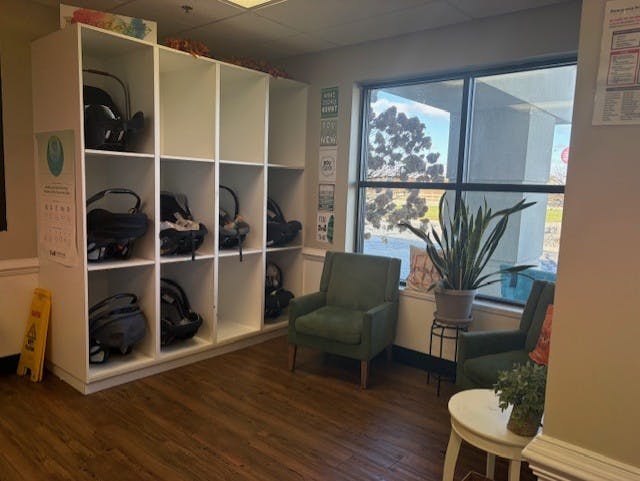 baby car seats stored in cubbies next to chairs and a window