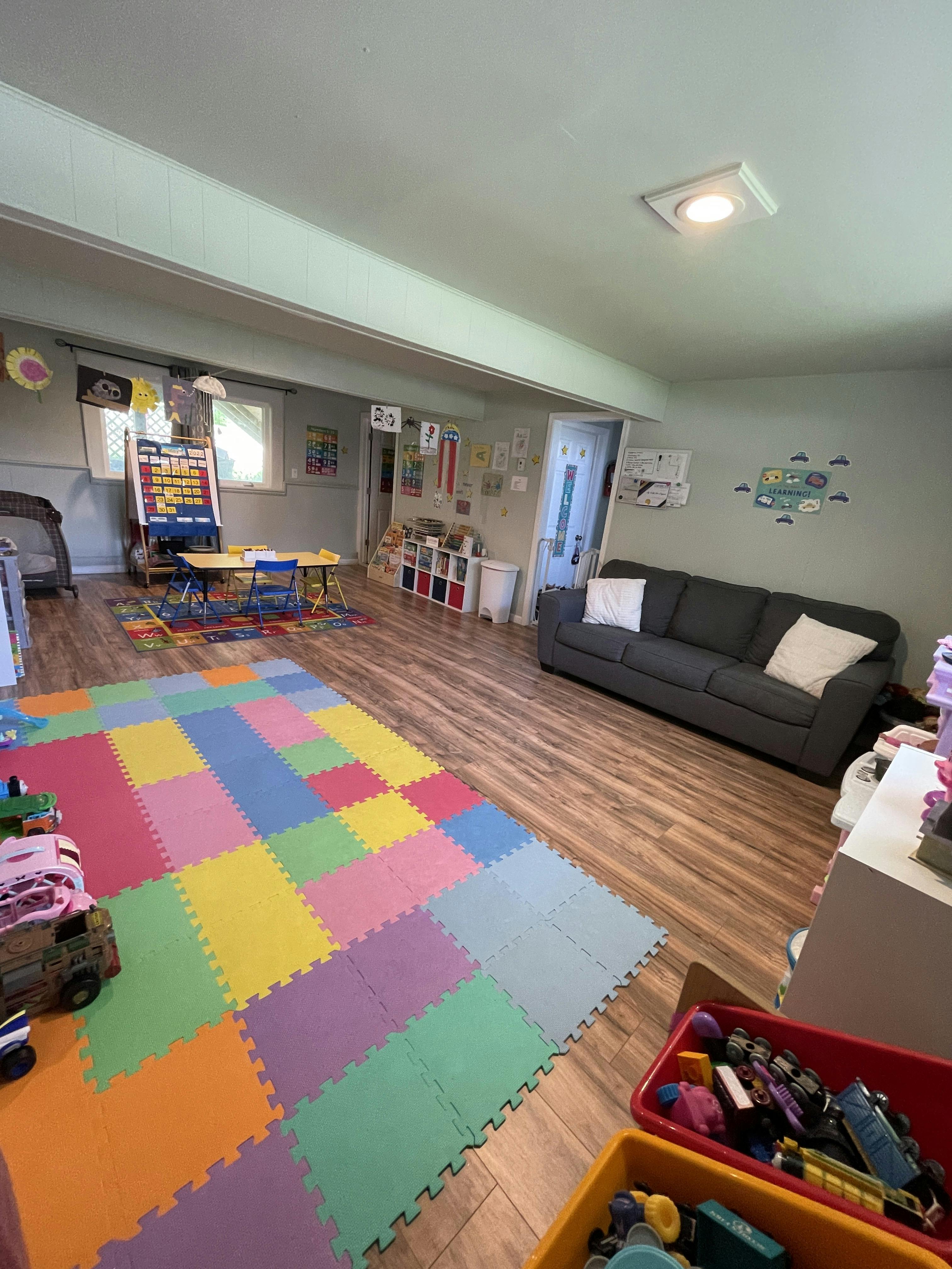Playroom with colorful floor mats, small table and chairs, and a sofa