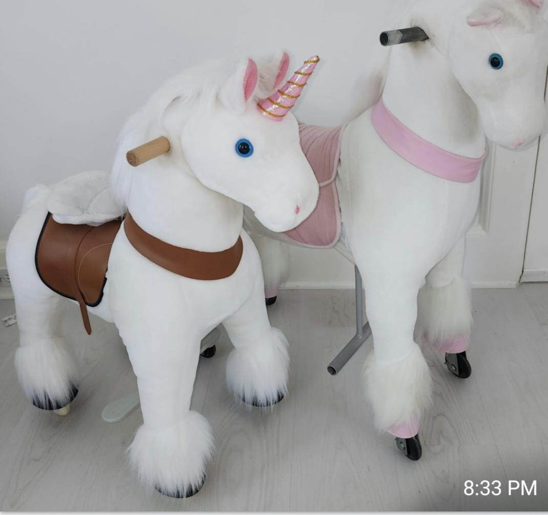 Two white unicorn ride-on toys with saddles