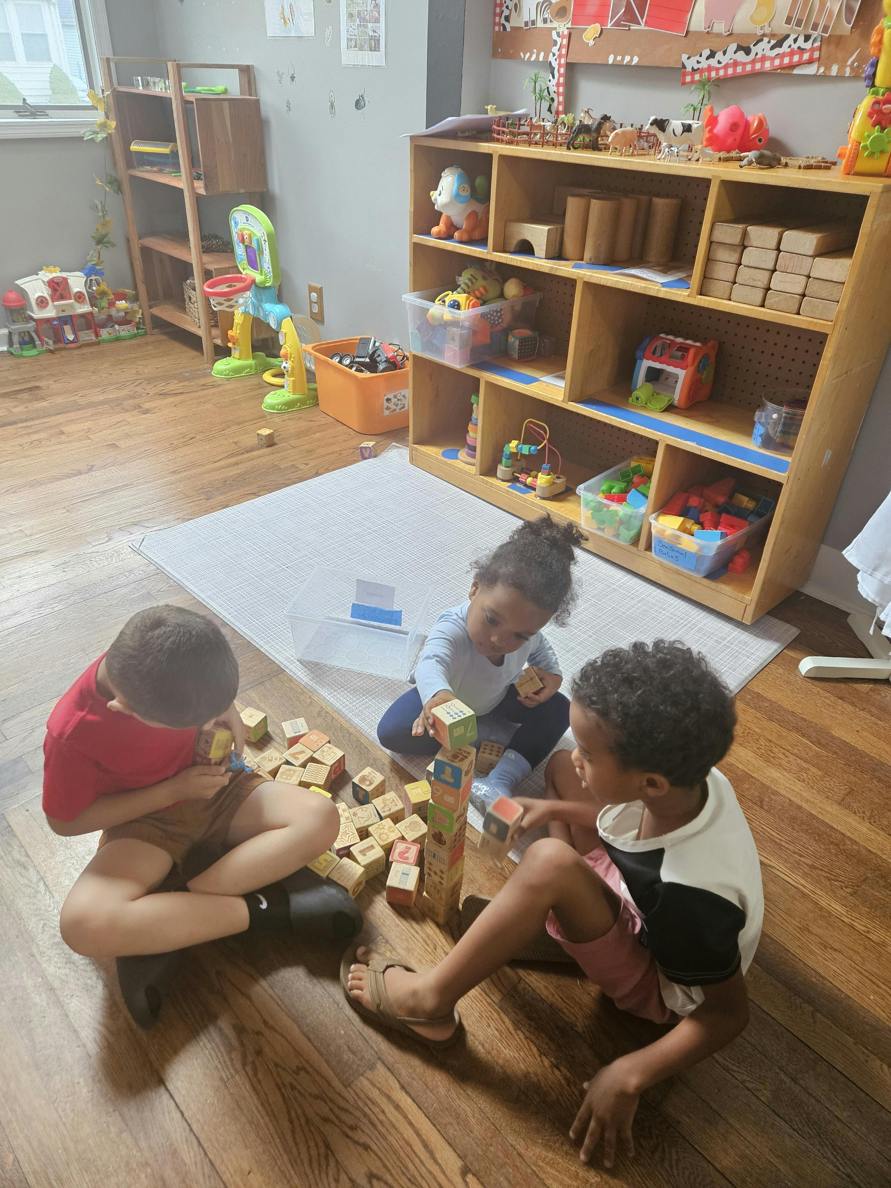 Three children playing with blocks on the floor in a classroom