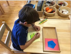 Child drawing on paper at a table