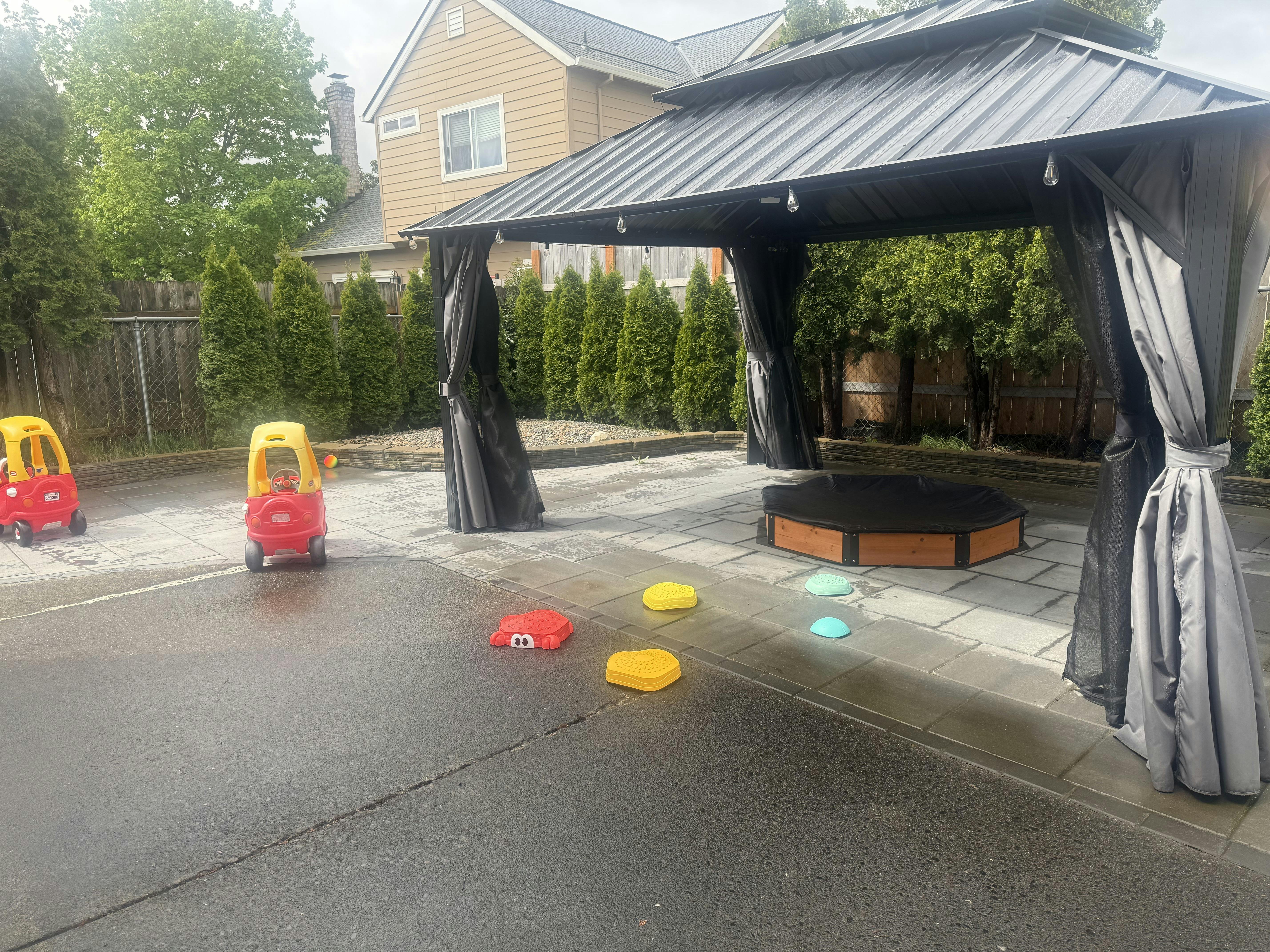 Two toy cars, a pop-up canopy, and play stepping stones on a patio