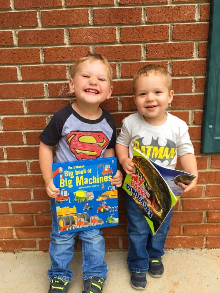 Two children holding books, one with "Big Book of Big Machines" and the other with "Dinosaurs"