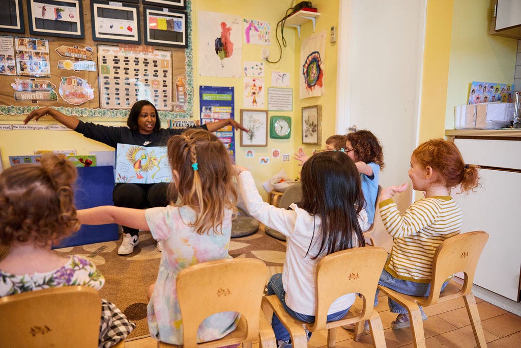 Teacher reading a book to a group of children in a classroom