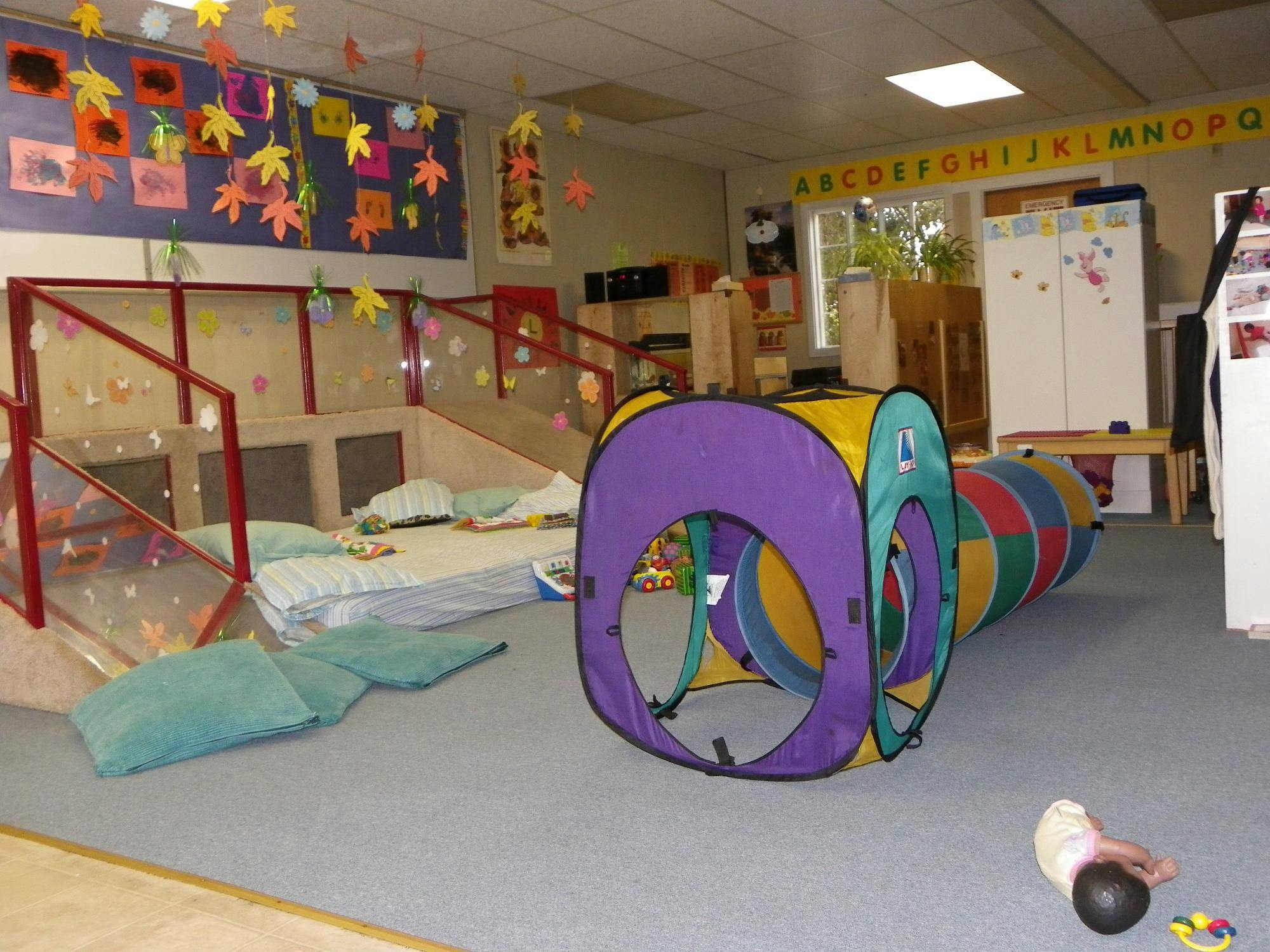 Indoor play area with a colorful tunnel and soft mats