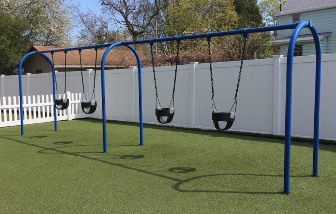 Blue swing set with four swings on green turf