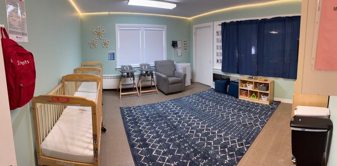 Nursery room with multiple cribs, a blue rug, and a window with window