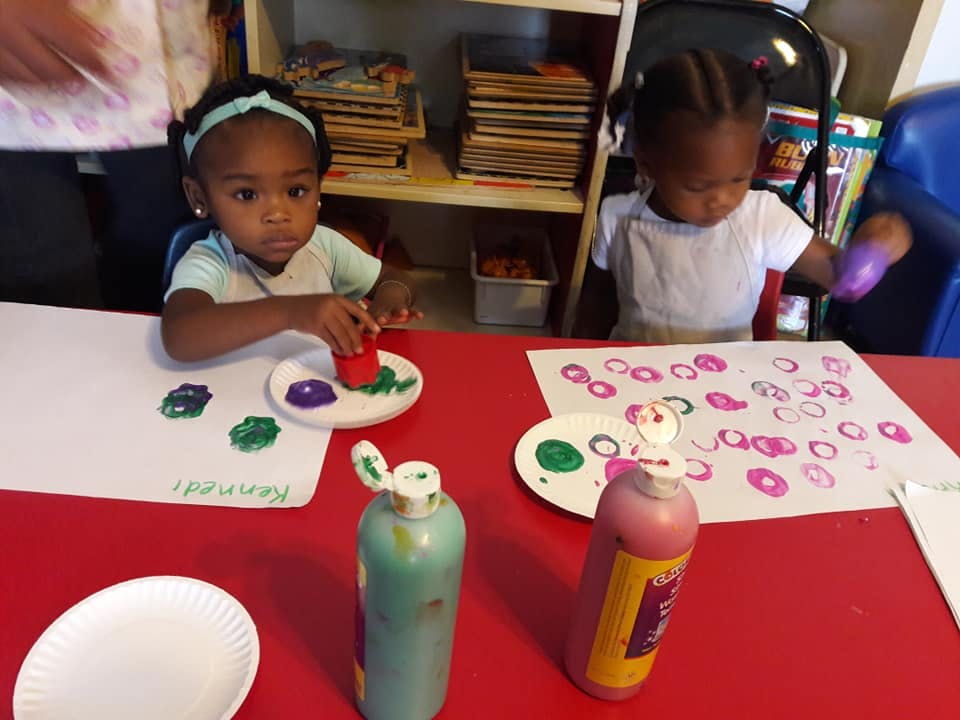 Two children painting at a red table