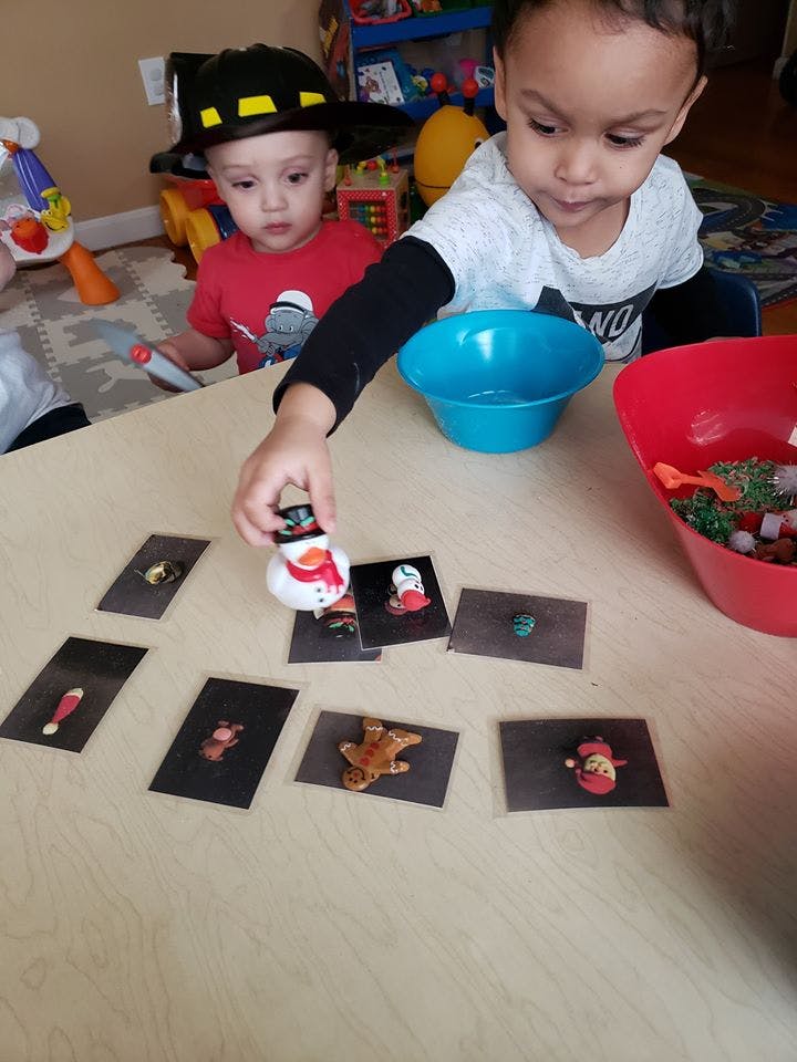Child playing with a snowman figurine and cards on a table